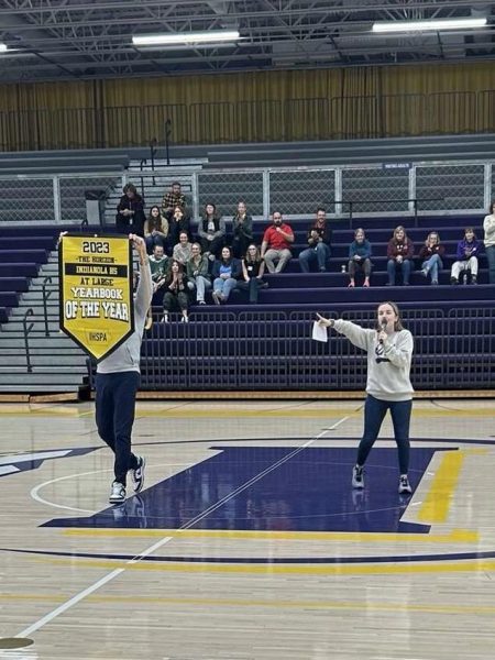 Adviser Emma Kinney tells the Indianola student body that their yearbook is one of the top in the state at the schools fall assembly Nov. 21. The Prize Patrol (aka Board member March Havnen) showed up with the banner.